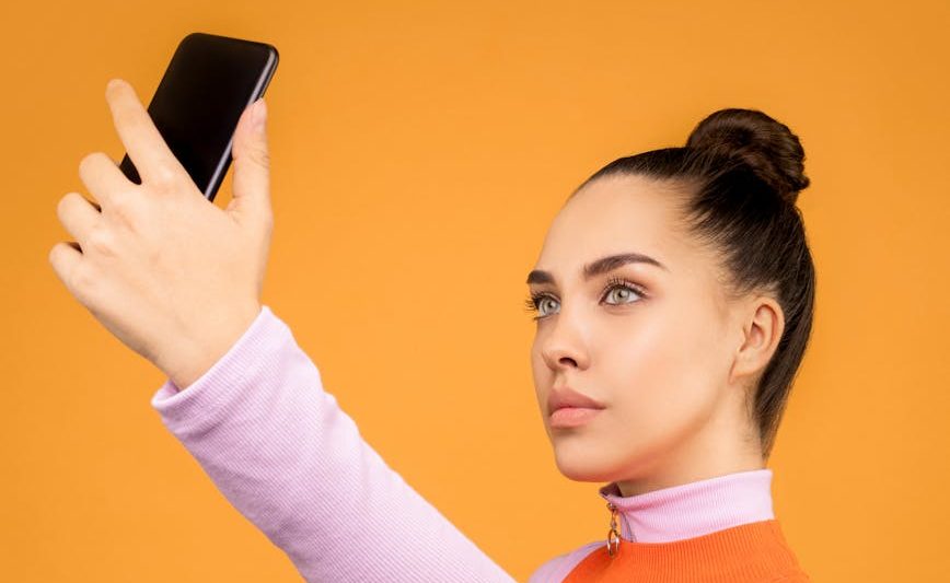 woman in pink and orange long sleeves taking selfie